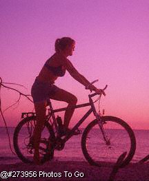 Woman on beach w/ bike at dusk